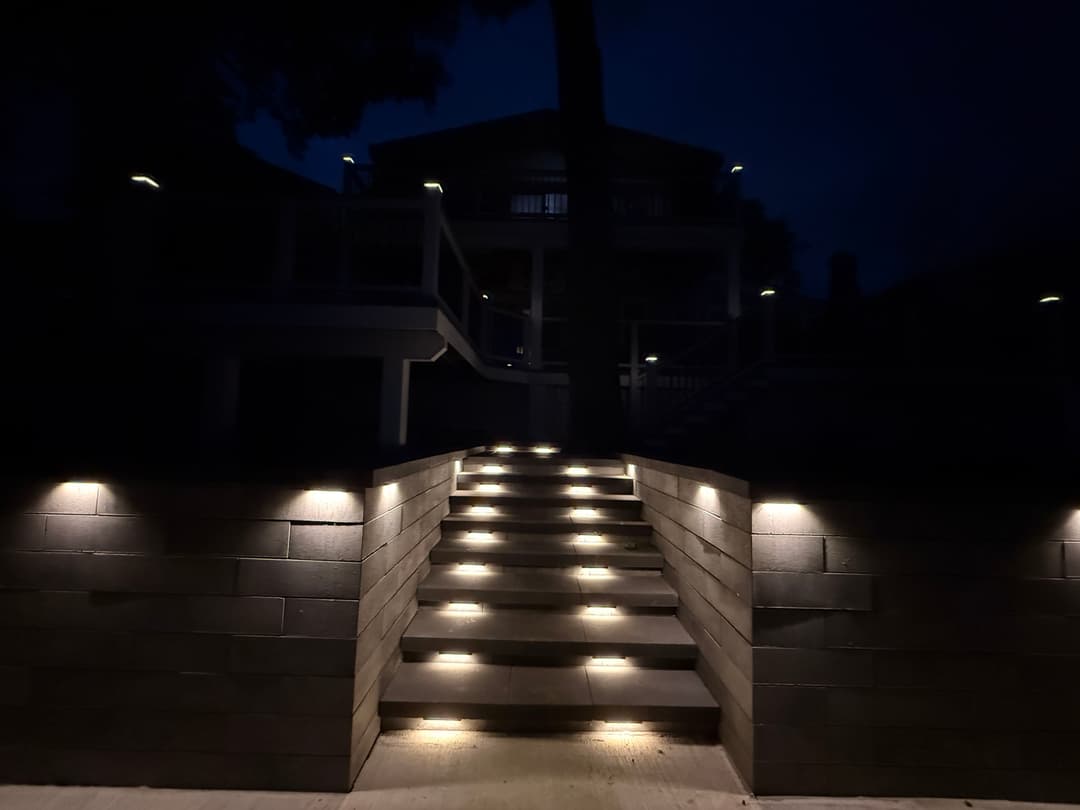Illuminated outdoor staircase leading to a house at night with modern lighting features.