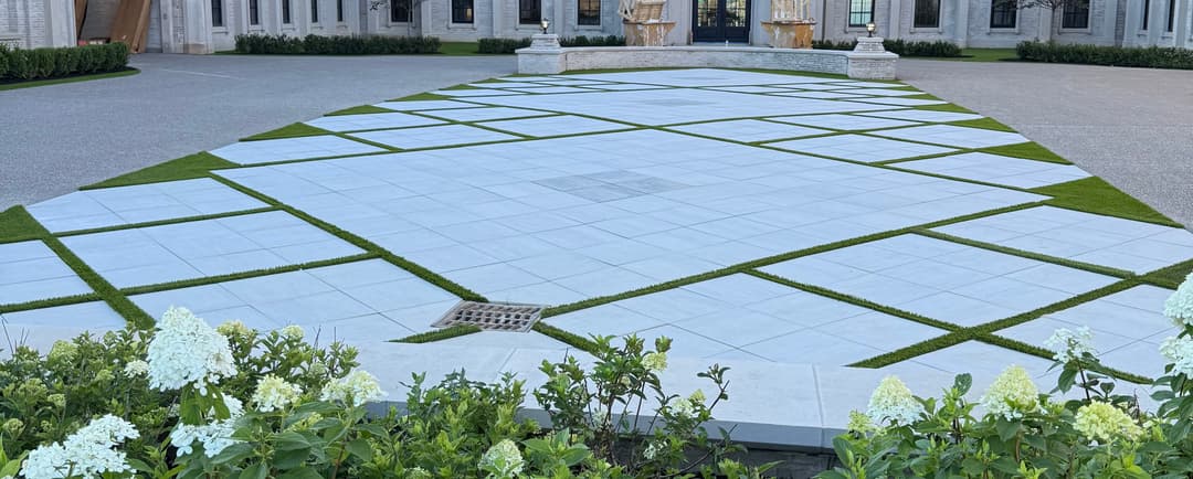 Modern landscaping design featuring geometric stone paving and lush green grass accents.