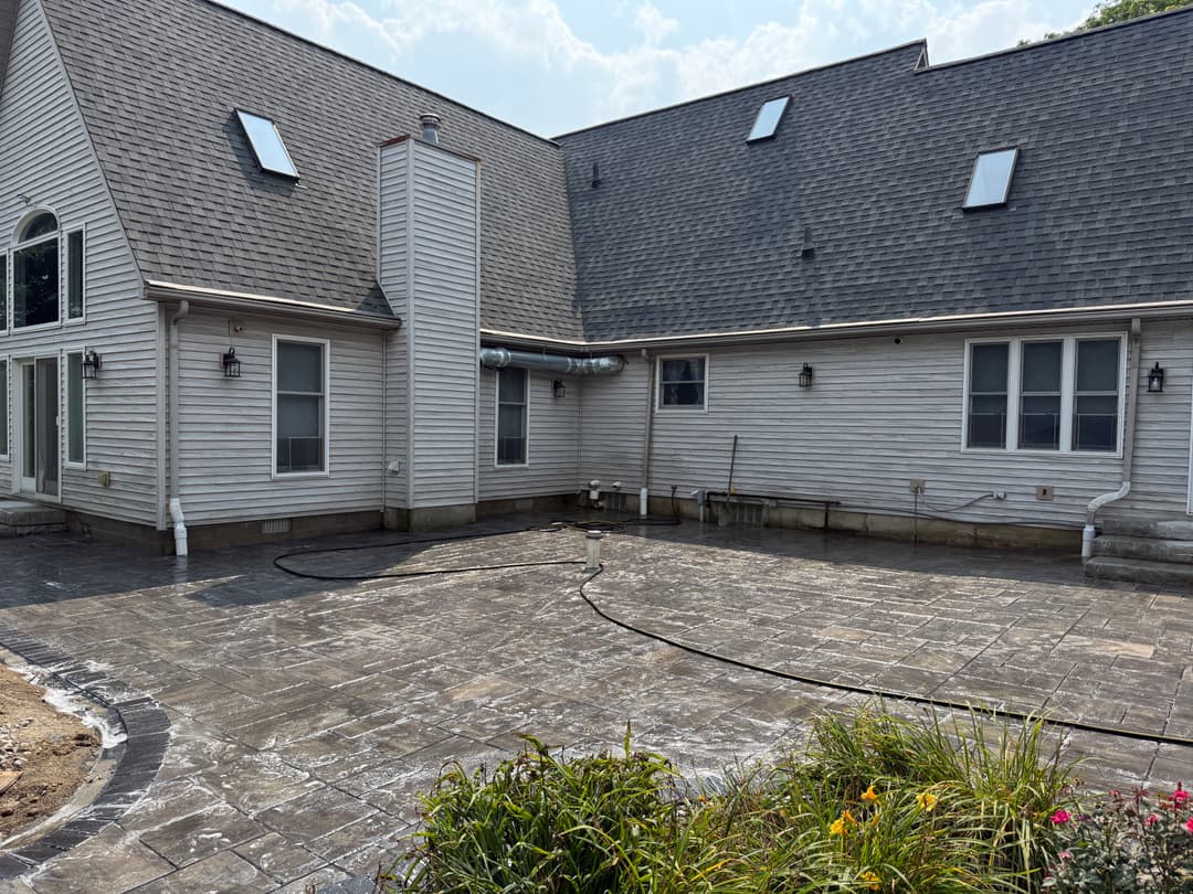 Stamped concrete patio and rear view of a residential home with landscaping.