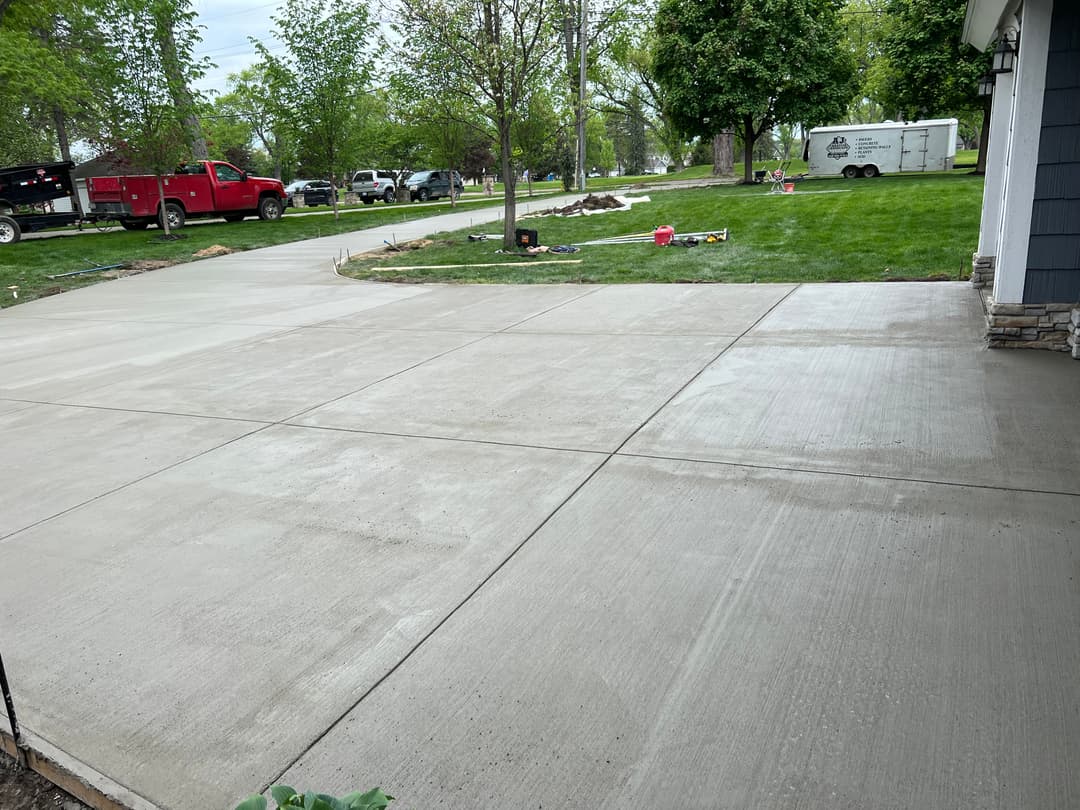 Freshly poured concrete driveway installation with landscaping in progress.