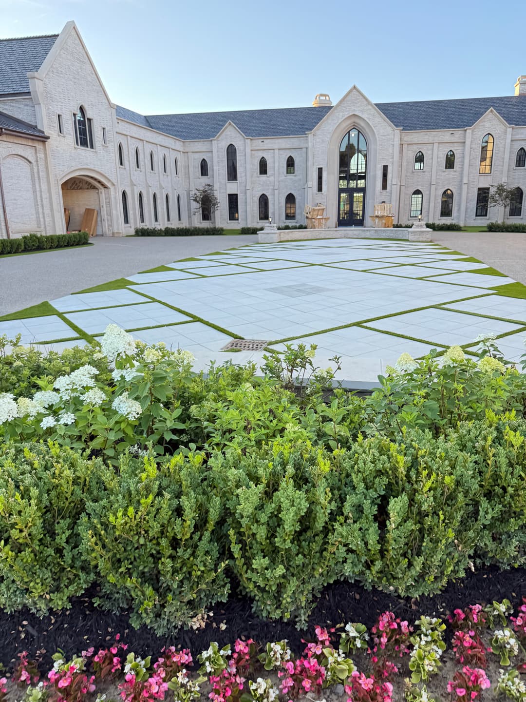 Elegant mansion exterior with landscaped garden and patterned stone courtyard.