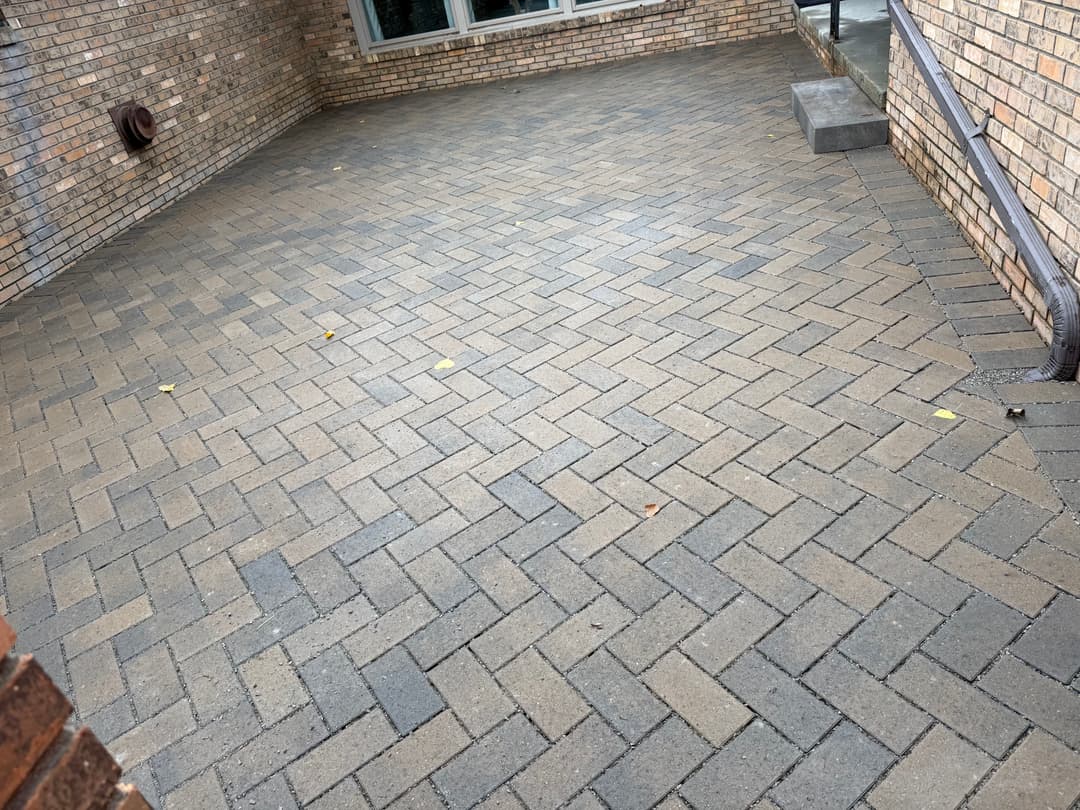 Paved brick patio area featuring a herringbone pattern in neutral tones.