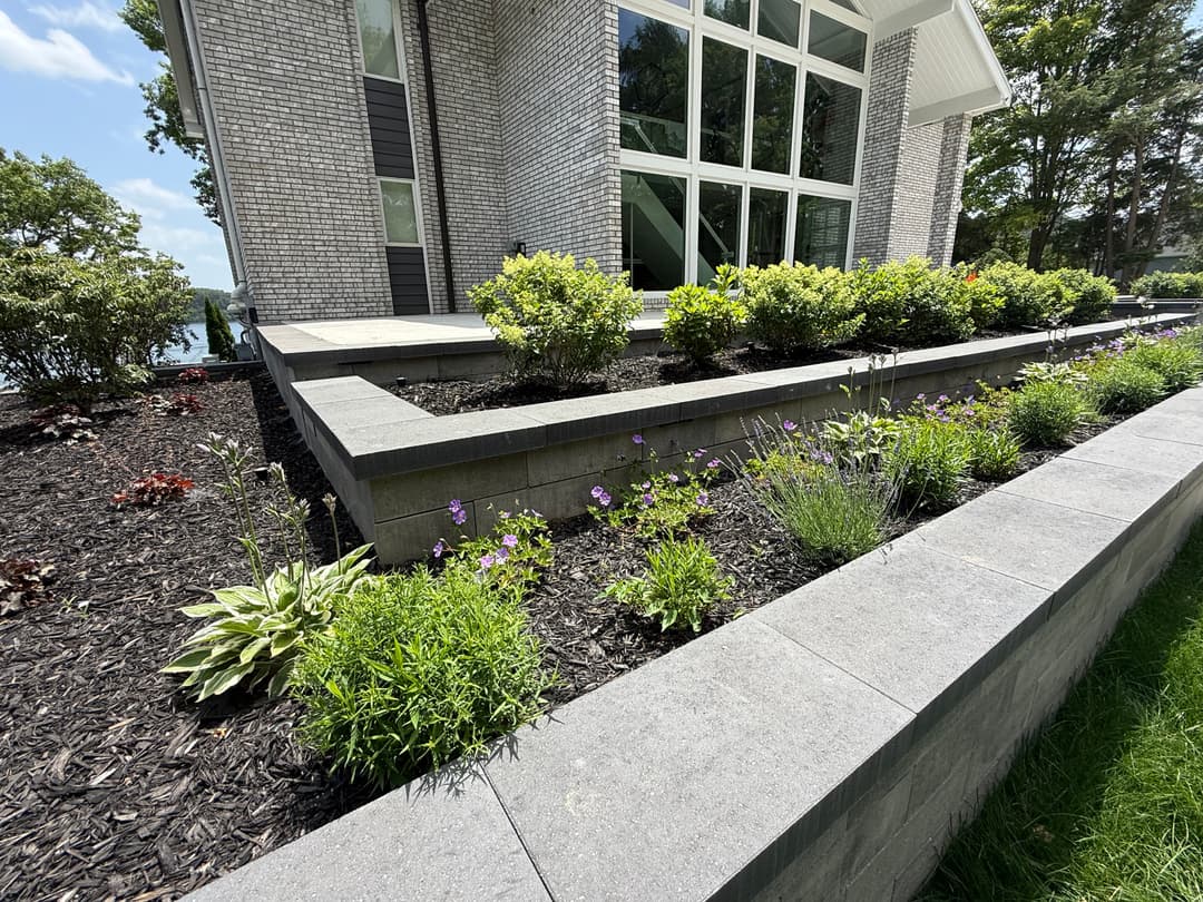 Modern landscaped garden with flowering plants and stone edging near contemporary home.