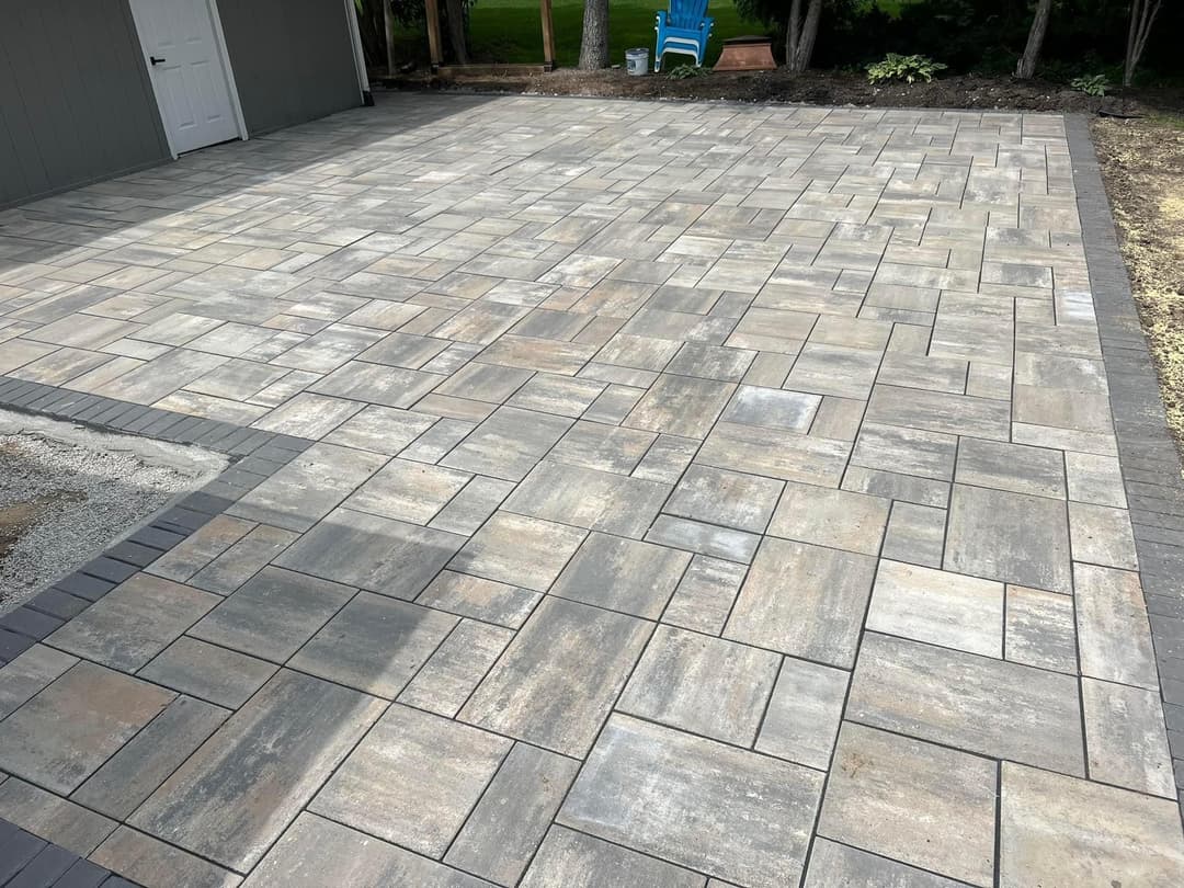 Newly installed gray paver patio with neatly arranged tiles and contrasting border.