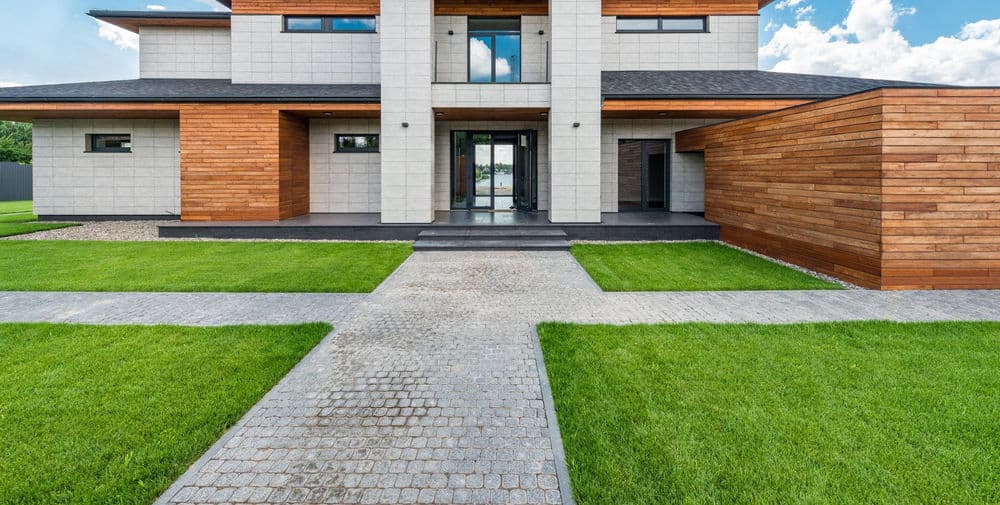 Modern two-story house with a wooden facade, large windows, and landscaped pathway.